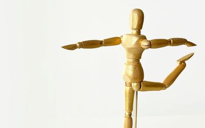 Silhouette of a person in a balancing yoga pose against a minimal background.